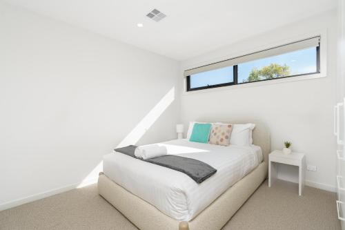 a white bedroom with a bed and a window at Mid-Century Home Near Hospital and Woden - Hosted by Canstay in Phillip