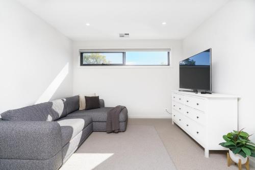 a living room with a couch and a flat screen tv at Mid-Century Home Near Hospital and Woden - Hosted by Canstay in Phillip