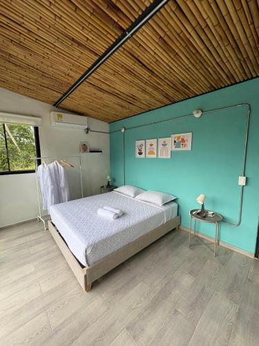 a bedroom with a bed and a blue wall at Cabaña Piamonte Villeta in Villeta
