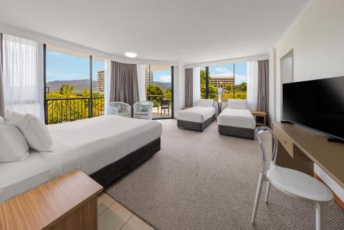 a hotel room with a large bed and a flat screen tv at Pacific Hotel Cairns in Cairns