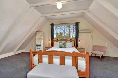 a bedroom with a bed and a chair in a attic at The Meadow Suite in Pokolbin
