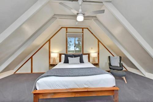 a bedroom with a bed with a ceiling fan and a chair at The Orchard Suite in Pokolbin
