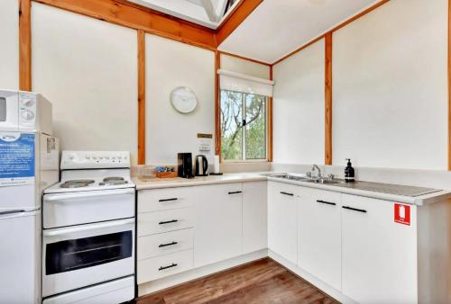 a kitchen with white cabinets and white appliances at The Orchard Suite in Pokolbin