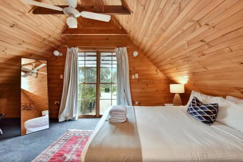 a bedroom with a large bed with a ceiling fan at The Ridge Stables in Pokolbin