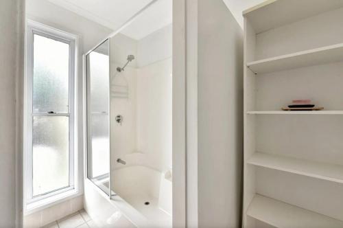 a white bathroom with a shower and a window at The Ridge Stables in Pokolbin