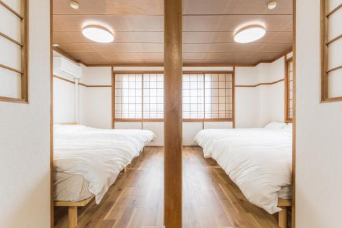 a row of beds in a room with windows at オオジンマチ ハイツ303 in Takayama