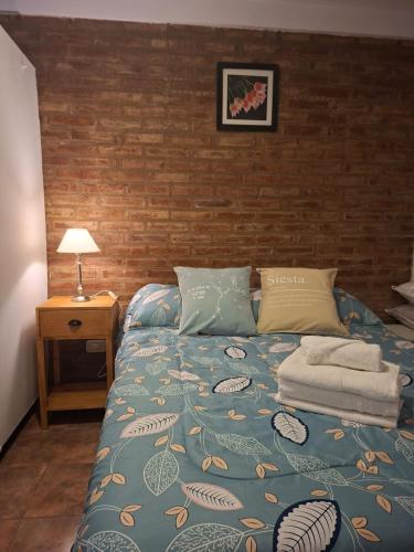 a bedroom with a blue bed with a brick wall at Barrio Aeropuerto 1 in RSA