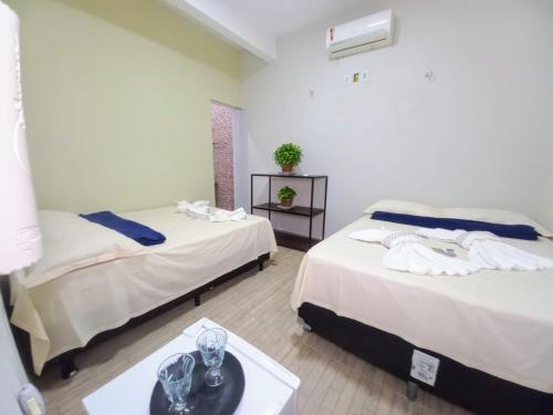 a room with two beds and a table with glasses on it at Pousada Aconchego em Mundaú in Trairi
