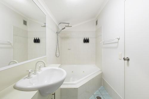 a white bathroom with a sink and a shower at Horizons Lake Jindabyne in Jindabyne