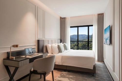 a hotel room with a bed and a desk and a window at Oakwood Cameron Highlands in Cameron Highlands