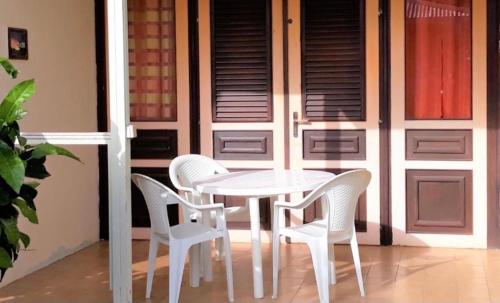 a white table and chairs in front of a door at Appartement Patronus à 3 min PLAGE POINTE MARIN in Sainte-Anne
