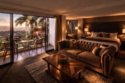 a hotel room with a bed and a couch and a balcony at Amega Hotel in Tagaytay