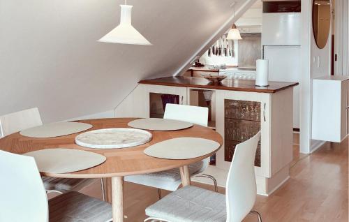 a dining room with a wooden table and white chairs at Skagenhuset Lejl 3 in Allinge