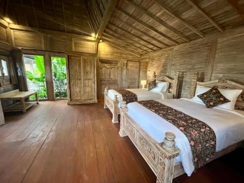 a bedroom with two beds and a wooden ceiling at Casa Tibubiu in Tabanan