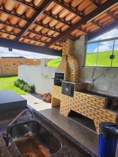 a outdoor kitchen with a brick fireplace with a stove at Rancho paraíso verde in Capitólio