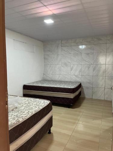 two beds are in a room with a wall at Casa de praia conde in Conde