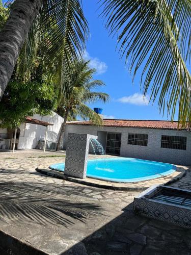 a swimming pool next to a building with a palm tree at Casa de praia conde in Conde