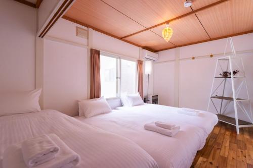 a bedroom with two beds with white sheets and a window at Villa Blanca Yoichi in Yoichi