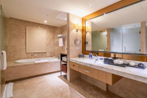 a bathroom with a tub and a large mirror at C&D Hotel Quanzhou in Quanzhou