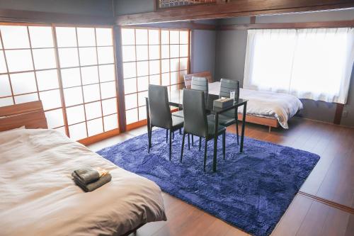a bedroom with a table and chairs and a blue rug at Udo Torii Gate Stay Yoi in Nichinan