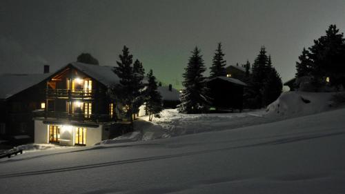 a house with lights on in the snow at night at Chalet Goldblick in Grächen