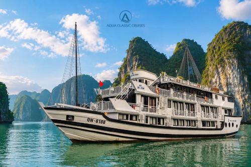 a boat in the water with mountains in the background at Aqua Classic Cruise in Ha Long