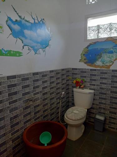 a bathroom with a toilet and a painting on the wall at Vila Graha Wisesa 3 in Kacomberan