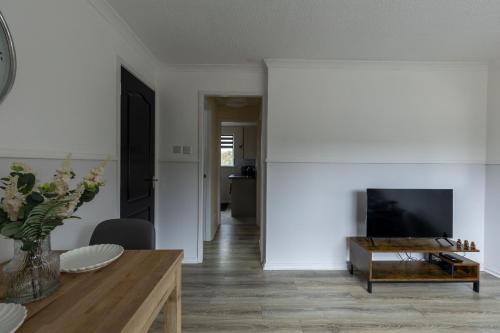 a living room with a tv and a table at Anderson Apartment in Airdrie