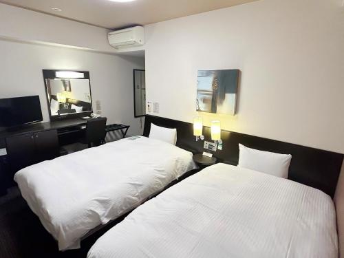 two beds in a hotel room with white sheets at Hotel Route-Inn Aomori Chuo Inter in Aomori
