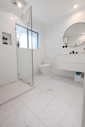a white bathroom with a shower and a toilet at Maleny Lakeside Retreat l 5BDRM l Firepit l Pets Ok in Maleny