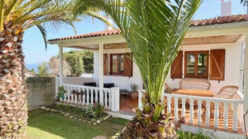 a white house with a porch and a palm tree at The Cliffs - Casa Alecrin in O Vicedo