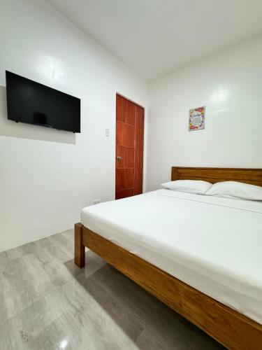 a bedroom with a bed and a flat screen tv at Southsea Staycation-couple in Nasugbu