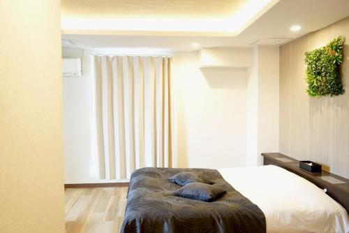 a bedroom with a bed and a window at Hotel WILL Kashiwa in Kashiwa