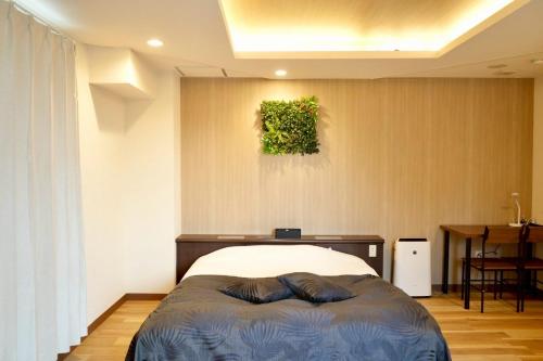 a bedroom with a bed and a painting on the wall at Hotel WILL Kashiwa in Kashiwa