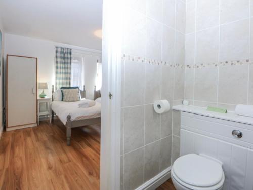 a bathroom with a toilet and a room with a bed at Tŷ Gareg in Gaerwen