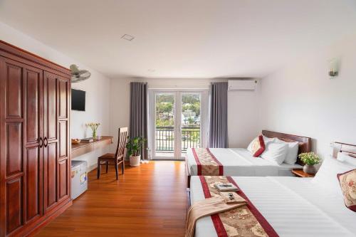 a hotel room with two beds and a desk at Liên Hương Hotel Đà Lạt in Kon Rung (1)