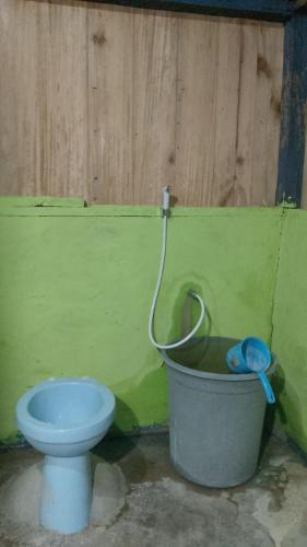 a bathroom with a toilet and a bucket at Kombrof Homestay & Dive Center in Waisai