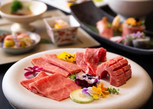 a plate of food with watermelon and other foods at Yufuin Hotel Shuhokan in Yufu