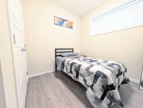 a bedroom with a bed with a checkered blanket at Villa Meadows Lethbridge in Lethbridge