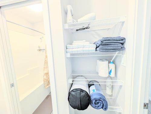 a small closet with white shelves and towels at Villa Meadows Lethbridge in Lethbridge