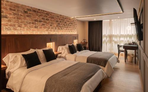 two beds in a hotel room with a brick wall at 5Q House Chapinero in Bogotá