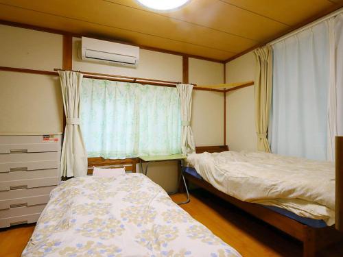 a bedroom with two beds and a window at ゲストハウス ソウル in Azumino