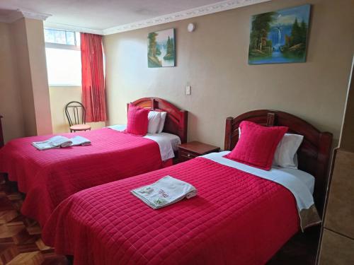 a hotel room with two beds with red sheets at Hotel Allegria in Quito