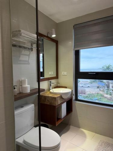 a bathroom with a toilet and a sink and a window at Anstay Beach Da Nang in Danang