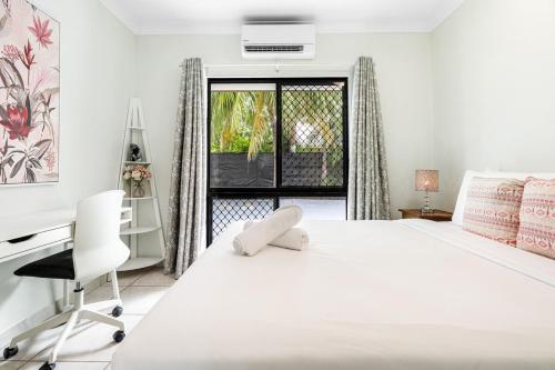 a white bedroom with a bed and a desk and a window at Zen Orient Luxurious 4BR Oasis with Private Pool in Leanyer