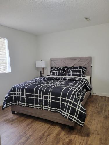 a bedroom with a bed with a black and white blanket at Executive Cozy 2bedroom Basement Suite in Brandon