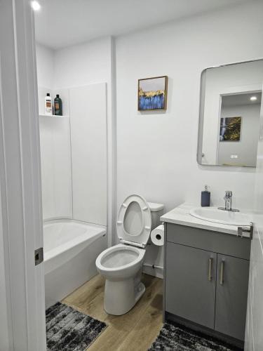 a white bathroom with a toilet and a sink at Transcona Stay in Winnipeg