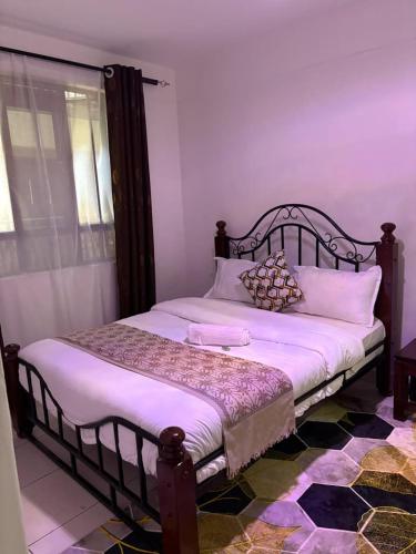 a bedroom with a large bed with white sheets and pillows at Primestay Suites in Eldoret