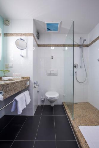 a bathroom with a toilet and a glass shower at Radisson Blu Hotel Karlsruhe in Ettlingen
