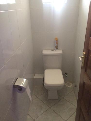 a white bathroom with a toilet and a toilet paper dispenser at Primestay Suites in Eldoret